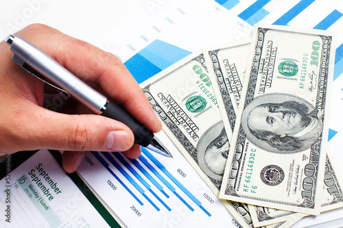 Photo: Hand with calculator and money. Hand with calculator and money.