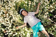 Photo: on a meadow boy in blue shorts and a cap is in daisies on a meadow boy in blue shorts and a cap is in daisies