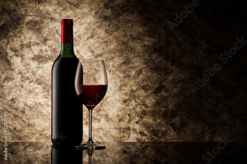 Photo: bottle with red wine and glass on a old stone bottle with red wine and glass on a old stone