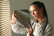 Young woman is standing near window and examining x-ray