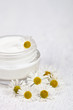 container with cream and chamomiles