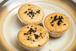 Freshly baked muffins in cups topped with chocolate .