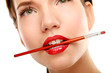 Woman's lips holding make up brush, isolated on white background