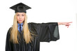 Young woman in graduation gown pointing on copy space