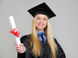 Smiling young woman in graduation gown showing diploma