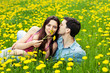 Positive couple on a field of dandelions .