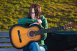 Foto: The girl sits with a guitar on a bench The girl sits with a guitar on a bench