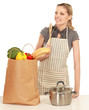 Woman in apron standing near table  with grocery bag
