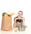 Woman in apron sitting on the desk with grocery bag
