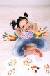 Young pretty painter with hands in paint, on gray background
