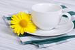 White cup and saucer with daisy flower on a wooden table