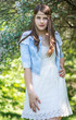 beautiful body of the young woman posing near the green tree