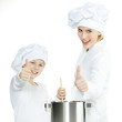 Photo: Mother and child having fun in the kitchen, show thumbs up Mother and child having fun in the kitchen, show thumbs up