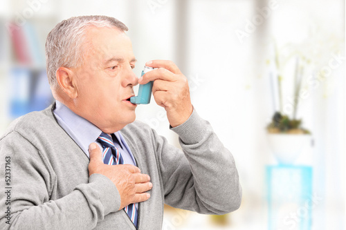 Photo: Mature man treating asthma with inhaler Mature man treating asthma with inhaler