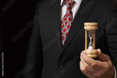 Photo: Businessman holding hourglass Businessman holding hourglass