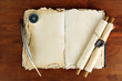 Open old book, scrolls and compass on wooden background