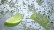 Fresh lime dropped into water with splash