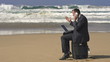 Angry businessman with cellphone on beach, super slow motion