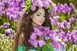 Beautiful young woman in lilac flowers, outdoors portrait