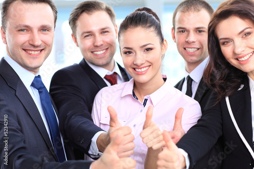Photo: Successful young business people showing thumbs up sign Successful young business people showing thumbs up sign