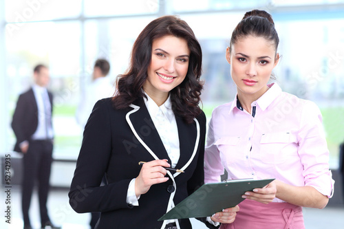 Photo: Two business women discussing project and smiling at office Two business women discussing project and smiling at office