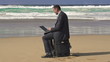 Businessman working on modern laptop on the beach