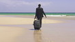 Businessman with suitcase walking on exotic beach, super slow mo