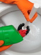 Gloved hand cleaning toilet bowl using brush