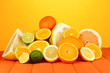 Lots ripe citrus on wooden table on orange background