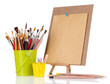 Small easel with sheet of paper with art supplies isolated