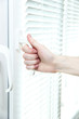 Someone opens metal-plastic window blinds closed