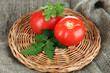 Fresh tomatoes on wicker mat on sackcloth background