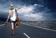 Young woman with guitar on the road and her vintage baggage