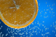 Slice of orange in water with air bubbles