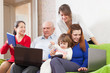 family enjoys on sofa with  laptops