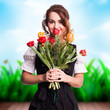 junge Frau im Dirndl mit einem Strauß Tulpen