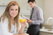 Young woman drinking orange juice in kitchen