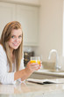 Woman reading while drinking orange juice