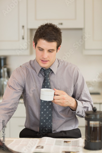 Photo: Man turning the page while drinking coffee Man turning the page while drinking coffee