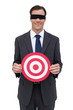 Photo: Blindfolded and smiling businessman holding a red target Blindfolded and smiling businessman holding a red target
