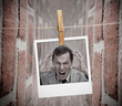 Instant photo of angry business man hung with peg