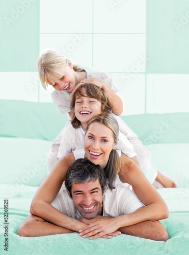 Photo: Smiling family piled on top of dad Smiling family piled on top of dad