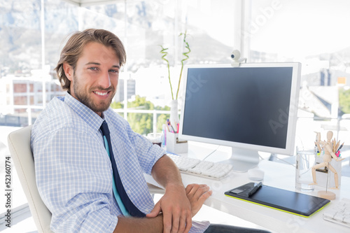 Photo: Smiling designer sitting at his desk Smiling designer sitting at his desk