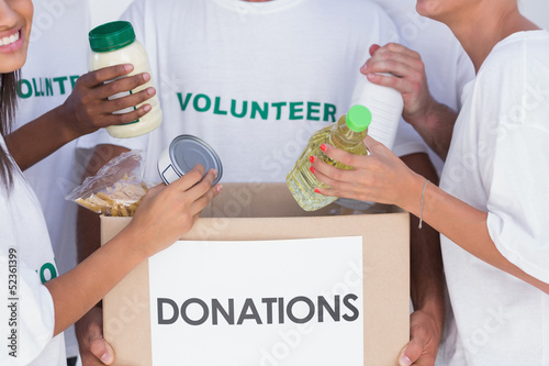 Photo: Volunteers putting food in donation box Volunteers putting food in donation box