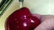 Lavando un pimiento rojo bajo el chorro de agua