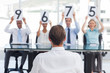 Panel of judges showing marks in front of an applicant