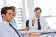 Businessman pointing someone while talking to colleagues