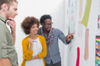 Smiling team of designers pointing at a wall