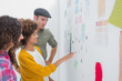Smiling team of designers working together and pointing at a wall