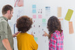 Team of designers working together and pointing at a wall